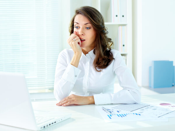 Concerned female office worker looking at the screen of laptop